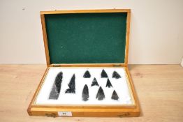 A glass display case displaying arrow tips, (10)
