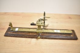 A 19th century brass tensile strength gauge with calibrated markings and mahogany step base,