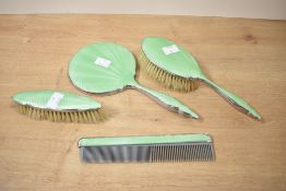 An Art Deco style green enamel vanity set, comprising of hand mirror, two brush and comb, (4)