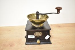 A cast iron coffee grinder having shaped handle and brass hopper, h16cm