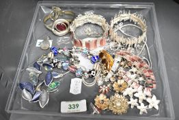 An assortment of costume jewellery, including paste set pieces, enamelled examples and a charm