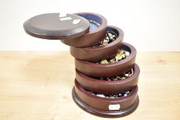 A wooden jewellery box, of oval form with sliding levels, containing a small collection of costume