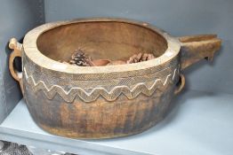 A large carved wooden bowl having shaped spout, handle and decorated with geometrical patterns,