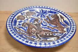 A ceramic charger hand coloured depicting Knight on horse back and lion, signed to reverse Sigloxx