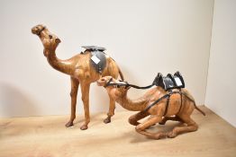 A pair of Liberty of London style Camel sculptures, having original saddles, glass eyes and aged