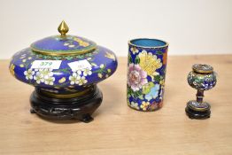 A Chinese cloisonne enamel lidded jar, of flattened form with finial topped cover and hardwood