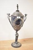 A silver-plated trophy cup supported with male figure raised on a circular base, decorated with