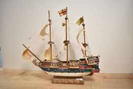 A vintage hand-painted miniature model ship on wooden base, measures 44cm 47cm.