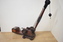 An early 20th century Wooden Crane having two hand cranks, hook on chain, four wheels to base,