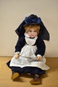 An early 20th century Bisque Headed Doll having sleep blue eyes, open mouth with four teeth showing,