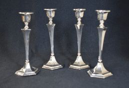 A group of four George V silver candlesticks, of hexagonal form having circular sconces, raised on