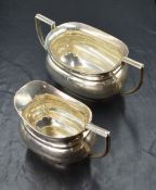 A George VI silver sugar and cream, of oval bulbous form, having angular handles raised on oval