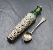 An Edwardian silver mounted scent bottle, the green glass bottle with a white metal cork top and