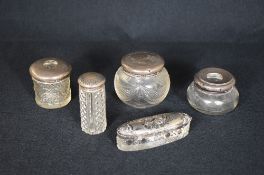 A group of five silver topped glass vanity wears, comprising powder pots and trinket boxes, all