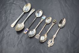 A group of seven silver and white metal teaspoons, including Old English pattern and souvenir