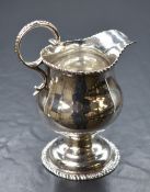 An early George III silver cream jug, of bulbous form having a gadrooned style rim, narrow spout