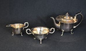 An Edwardian silver three piece tea set, comprising a teapot, sugar and cream, of circular form