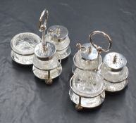 A pair of three piece cruet sets, the silver stands containing cut glass salt, pepper and