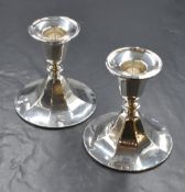 A pair of early George V silver candlesticks, of squat form having circular moulded sconces with