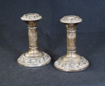 A pair of Edwardian silver candlesticks, having embossed decoration to the sconces and further