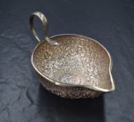 An Eastern white metal sauce boat, of traditional form having a narrow spout opposed by a snake s-