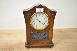 An early 20th century mantel clock having carved floral decoration and raised on bun feet, h25cm