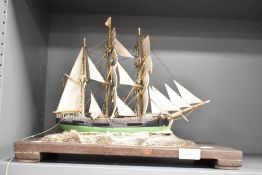A 20th century ship model diorama, fully rigged, raised on a sea bed supported on a wooden base,