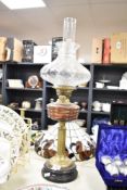 A 19th century oil lamp having double burners, brass body and glass shade, raised on a ceramic black