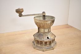 A cast metal coffee grinder having octagonal body decorated with ribbons and leaf panels,
