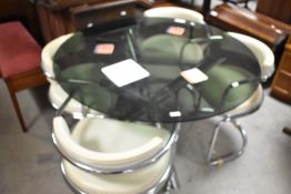 A vintage smoked glass dining table having circular top and chrome supports and four vinyl and