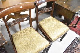 A pair of 19th Century mahogany formal dining chairs in the Regency design having shaped rail backs,