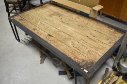 A 'Restoration Hardware' plank style coffee table having metal legs, in the rustic industrial style,