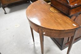 A 19th Century mahogany demi lune fold over table having inlaid acorn decoration in the Sheraton