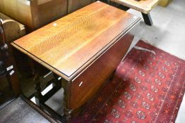 An early 20th Century oak dining table having twist gate leg