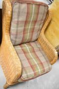 A wicker armchair with tweed style cushions
