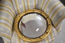 A mid 20th Century butlers convex mirror in the Regency style having gilt painted frame and black