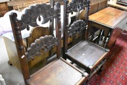 A pair of Vernacular design solid seat hall chairs having carved figural and acorn design