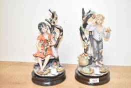 Two large vintage Capodimonte style figures depicting a male and female child amongst fruit trees,