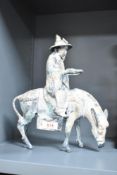 A Japanese 'toyo' cast metal figure of a gentleman on horse back, roughly cast with gilt paint and