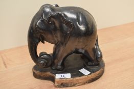 A black elephant sculpture raised on a wooden base, h18.5cm