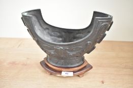 A metal Chinese archaic style bowl raised on a wooden base, L27cm