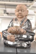 A stoneware Buddha sculpture sitting cross legged holding a candle, h32cm
