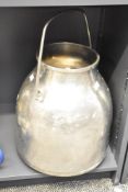 A vintage stainless steel milk churn of traditional form with swing over handle