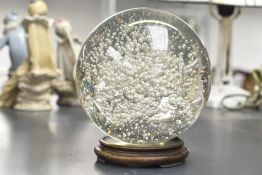A clear glass ball having controlled bubble decoration, raised on a wooden stand, h13.5cm, h16cm
