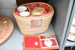 A wicker hamper containing a Chinese tea pot and 2 cups both decorated with geometrical foliage