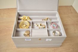 A beige Stackers jewellery box, comprising three sections containing a small collection of costume