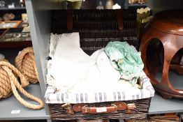 A reproduction lined hamper containing a selection of table linen