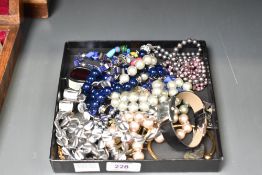An assortment of costume jewellery, including black and purple pearls, beaded jewellery, brooches