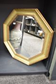 An octagonal mirror having a bevelled edge and green and gold colour frame, w57cm