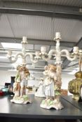 A pair of 19th century porcelain 4 branch candlabras depicting male and female figures with money